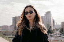 Person wearing sunglasses on a sunny sidewalk