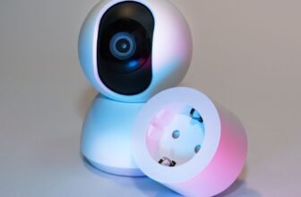 Smart home security camera and plug socket on a neutral background.