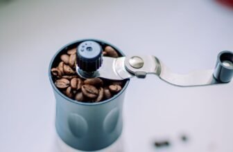 Close-up of a manual coffee grinder filled with coffee beans.