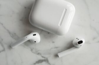 High-quality image of wireless earbuds and charging case on marble surface, showcasing modern technology.