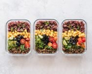 Colorful healthy meal prep with corn, olives, tomatoes, and lentils in glass containers. Perfect for mindful eating.