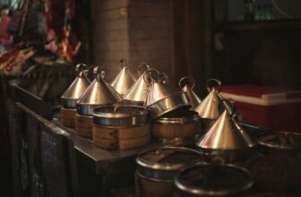 Close-up of traditional metal tiffin carriers in dim lighting at an indoor market.