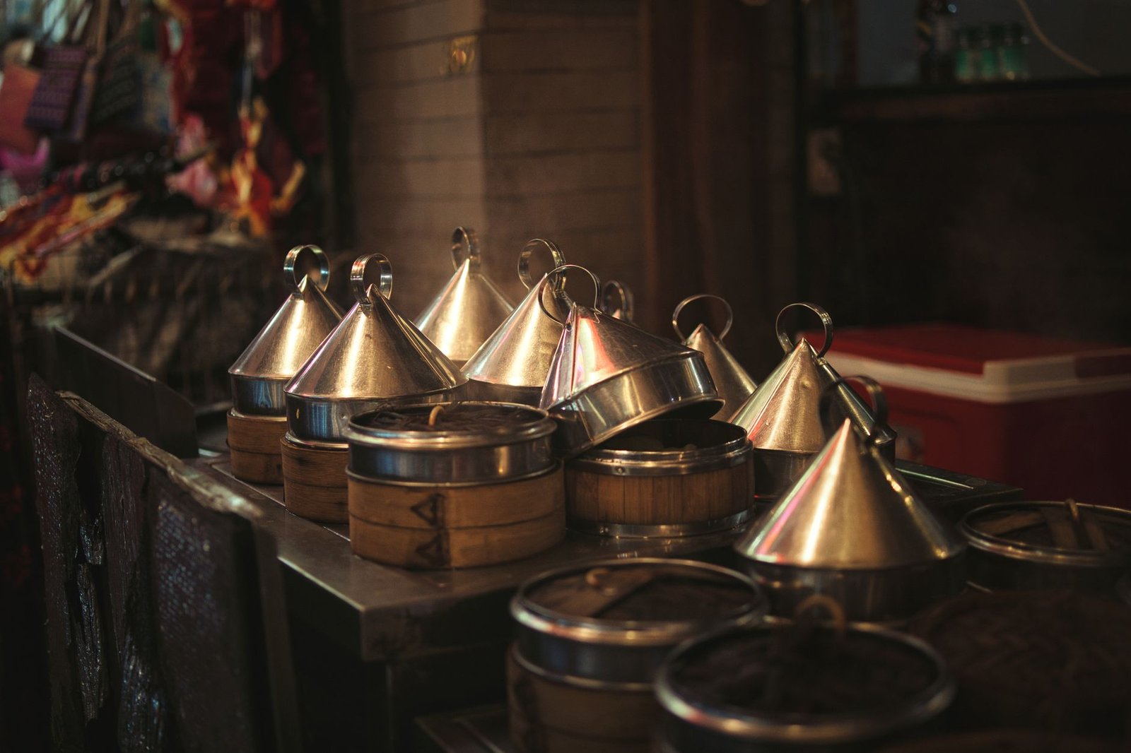 Close-up of traditional metal tiffin carriers in dim lighting at an indoor market.