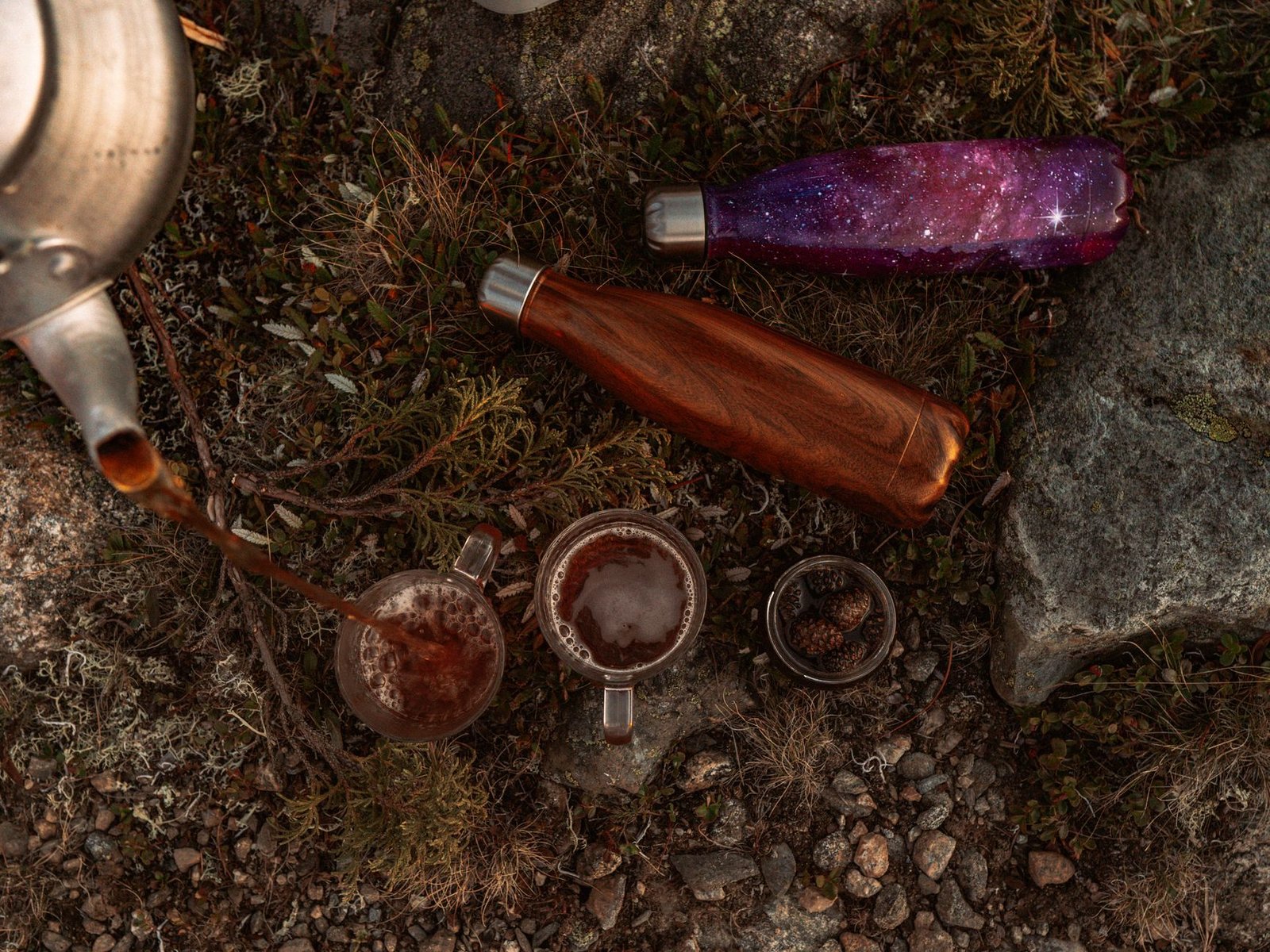 Relaxing beverages poured in nature, featuring eco-friendly bottles on rocky terrain.