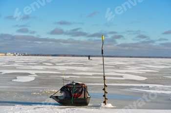 Ice fishing equipment on a frozen lake with a person in the distance