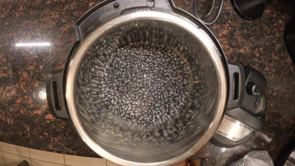 Top view of putting black beans and water to an instant pot for preparing a meal.