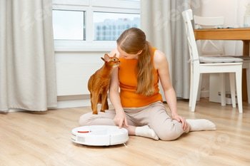 Woman turns on a robot vacuum cleaner