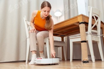 Woman turns on a robot vacuum cleaner