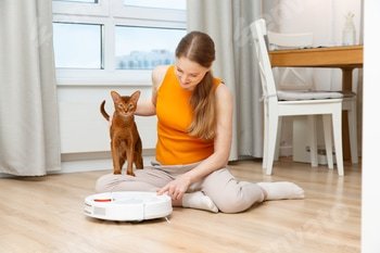 Woman turns on a robot vacuum cleaner